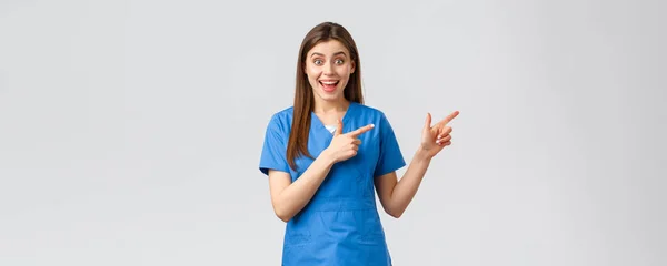 Sağlık çalışanları, virüsü, sigortayı ve ilaç konseptini engelleyin. Heyecanlı, mutlu, mavi önlüklü kadın hemşire ya da doktor parmaklarını göstererek eğleniyor, tanıtım ya da iyi haberler hakkında bilgi veriyor. — Stok fotoğraf