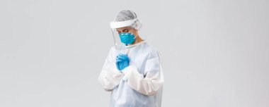 Covid-19, virüsün önlenmesi, sağlık, sağlık çalışanları ve karantina konsepti. Umut verici doktor ya da hemşire kişisel koruyucu giysi, yüz kalkanı ve tıbbi maske, hastaların koronavirüsü iyileştirmesi için dua ediyor.