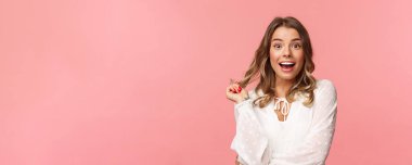 Şaşkın ve şaşkın sarışın kız. Güzellik salonuna giderken kız arkadaş hikayesine ilgi duyan güzel kız. Parmak ucunda yuvarlanan saç teli ve mutlu bir gülümsemeyle hayret dolu bir kamera.