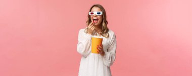 Boş zaman, dışarı çıkma ve bahar konsepti. Beyaz elbiseli çekici bir kadının portresi sinemada tam ekran film izlemekten zevk alıyor, patlamış mısır yiyor ve 3D gözlük takıyor.