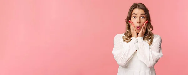 De ninguna manera, qué historia. Chica rubia aturdida y sorprendida escuchando chismes con emoción e interés, tomados de la mano en las mejillas dicen wow y miran asombrada cámara, de pie fondo rosa —  Fotos de Stock