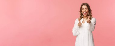 İşe alım, seçim ve güzellik konsepti. Çekici ve neşeli sarışın sevimli kız kameraya silah doğrultuyor, takımından birini seçiyor, katılmak istiyor, ya da resmi olmayan selamlaşmalar yapıyor, gülümsüyor.