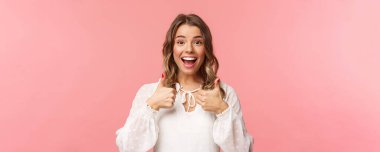 Tatmin olmuş ve etkilenmiş sarışın kızın yakın plan portresi, gittiği yer ya da kafe hakkında olumlu görüş bildirin, beğendiğiniz ve onayladığınız, gülümseyen mutlu, pembe arka plan