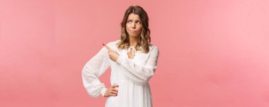 Ürünlere şüpheyle bakan, sırıtan, endişeli, somurtan, düşünceli, sol üst köşeyi işaret eden, yargılayan, tereddütle karar veren şüpheci genç sarışın kız.