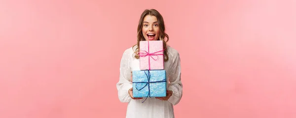 Fiestas, celebración y concepto de mujer. Retrato de chica alegre feliz le gusta celebrar cumpleaños y recibir regalos, sosteniendo dos cajas de regalo y cámara sonriente, fondo rosa — Foto de Stock