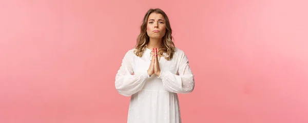 Portrait of hopeful clingy girlfriend, blond girl begging for favor in white dress over pink background, sobbing make cute eyes, pleading or prayed, say please, want something bad — Stok Foto