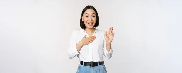 Obrázek roztomilé mladé ženy kancelářské pracovnice, asijské dívka student zvedá ruku nahoru a dát dlaň na hrudník, jméno sama, představit, dělat slib, stojící nad bílým pozadím — Stock fotografie