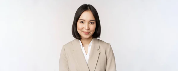 Κοντινό πλάνο πορτρέτο της επιχειρηματία, ασιατική γυναίκα επιχειρηματίας στο κοστούμι, χαμογελώντας και αναζητούν επαγγελματίες, στέκεται πάνω σε λευκό φόντο — Φωτογραφία Αρχείου