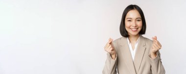 Neşeli Asyalı satıcı, gülümseyen ve işaret gösteren, beyaz arka planda takım elbise içinde duran