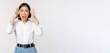 Paniklemiş endişeli Asyalı bir kadın resmi. El ele tutuşmuş, endişeleniyor, hayal kırıklığına uğramış ve beyaz arka plana karşı korkmuş.