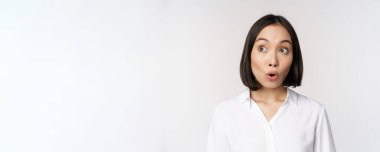 Asyalı genç bir kadının sol üst köşeye bakıp şaşırdığı portreyi yakından çek. Etkileyici, etkileyici, beyaz arka planda duran duygu.