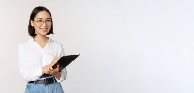 Gülümseyen Koreli ofis kadını, panoya yazı yazan şirket çalışanı, notlar alan, beyaz arka planda duran