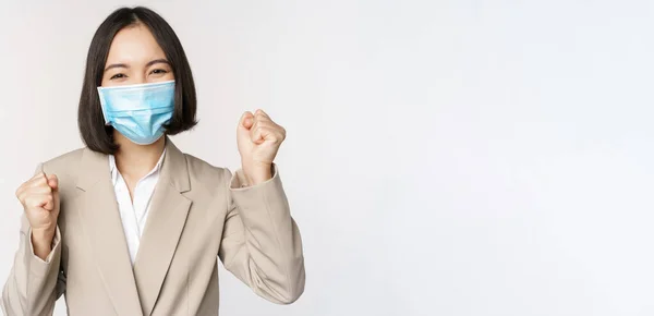 Concepção de coronavírus e pessoas de negócios. Empresária feliz na máscara médica dançando, celebrando o sucesso, realização, de pé sobre fundo branco — Fotografia de Stock