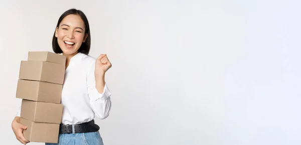 Enthusiastische koreanische Shopperin, die Schachteln hält und glücklich lächelt, vor weißem Hintergrund stehend — Stockfoto