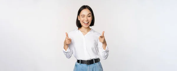 To jsi ty, gratuluju. Usmívající se atraktivní asijská žena, podnikatelka ukazuje prsty na kameru s potěšenou tváří, lichotí, zve vás, stojí nad bílým pozadím — Stock fotografie