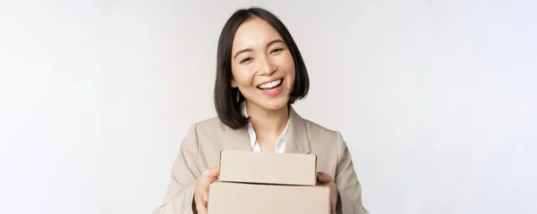 Imagem da vendedora asiática, mulher de negócios dando caixas com ordem, entregar ao cliente, de pé em terno sobre fundo branco — Fotografia de Stock