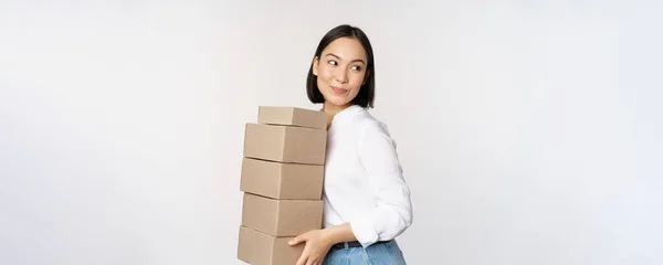 Porträt einer jungen asiatischen Frau, die Kisten hält und Waren transportiert. Koreanische Unternehmerin montieren Ordnung, stehend voer weißen Hintergrund — Stockfoto