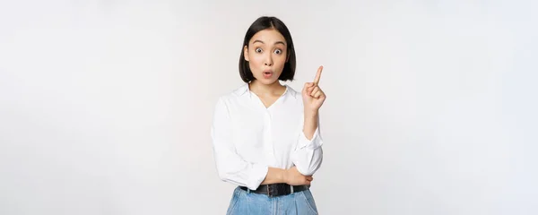 Eureka. Junge intelligente asiatische Mädchen hat eine Idee, hebt den Finger nach oben, teilt ihren Plan, zeigt auf die Spitze, steht über weißem Hintergrund — Stockfoto
