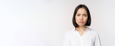 Üzgün ve kasvetli genç Asyalı kadın somurtuyor, somurtuyor, somurtuyor, beyaz arka plan