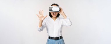 Vr sohbet. Asyalı kız sanal gerçeklik gözlükleriyle merhaba diyor, coşkuyla gülümsüyor, iletişim konsepti ve gelecek teknolojisi, beyaz arka plan