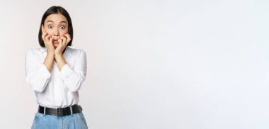 Korkmuş Asyalı bir kadının portresi. Korkunç, ısıran parmakları izliyor. Korkmuş bir şekilde kameraya bakıyor.