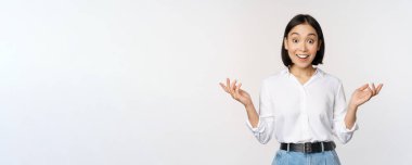 Heyecanlı genç Asyalı kadın, inançsızlıktan mutlu görünüyor, şaşırtıcı haberler duyuyor, şaşırtıcı bilgiler, beyaz arka planda duruyor.