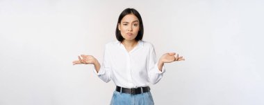 Kafası karışmış Asyalı ofis müdürü, omuz silken ofis çalışanı ve cahil görünen, beyaz arka plana karşı kafası karışmış bir kadın.