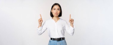 Şüpheci iş kadını, Asyalı ofis müdürü, parmaklarını kaldırıyor ve şüpheci, tereddütlü, beyaz arka planda duruyor.