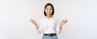 Heyecanlı genç Asyalı kadın, inançsızlıktan mutlu görünüyor, şaşırtıcı haberler duyuyor, şaşırtıcı bilgiler, beyaz arka planda duruyor.