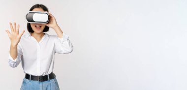 Vr sohbet. Asyalı kız sanal gerçeklik gözlükleriyle merhaba diyor, coşkuyla gülümsüyor, iletişim konsepti ve gelecek teknolojisi, beyaz arka plan