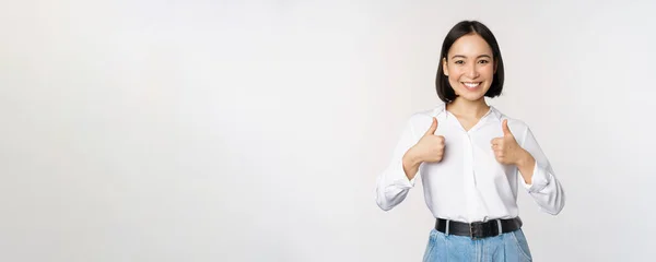 Afbeelding van mooie volwassen aziatische vrouw tonen duimen omhoog, het dragen van formele kantoor, universiteit kleding, aanbevelen bedrijf, staande over witte achtergrond — Stockfoto