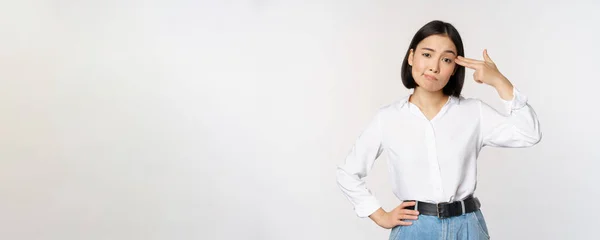 머리에 손가락을 대고 하얀 배경 위에서 있는 피곤 한 아시아 여인의 모습 — 스톡 사진