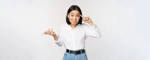 ¿Estás loco? Retrato de una joven mujer asiática frustrada, rodar el dedo cerca de la cabeza y el srugging, alguien loco o estúpido, de pie sobre fondo blanco —  Fotos de Stock