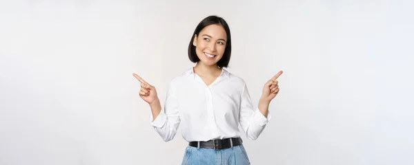 Obrázek krásné asijské ženy ukazuje prsty vlevo a vpravo, rozhodování, zobrazení dvou variant volby, stojící nad bílým pozadím — Stock fotografie