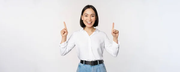 Image de femme d'affaires confiante souriante, dame asiatique pointant les doigts vers le haut, montrant des informations de bannière ou de vente, debout sur fond blanc — Photo