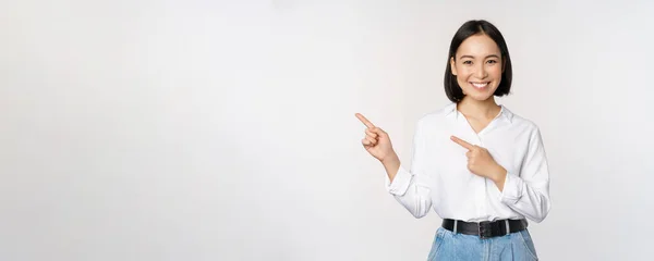 Bild einer lächelnden jungen Bürokauffrau, asiatischer Unternehmer zeigt mit dem Finger nach links, zeigt Kundeninformationen, Banner seitlich auf Kopierfläche, weißer Hintergrund — Stockfoto