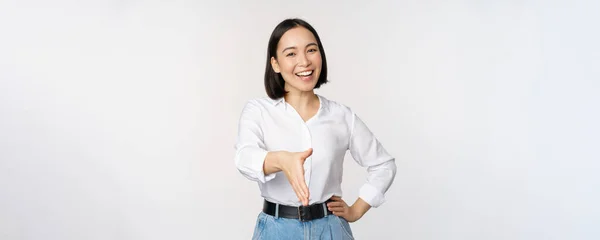 Wizerunek pewnej siebie azjatki uśmiechniętej, wyciągnij rękę na uścisk dłoni powitalny gest, witaj, stojąc nad białym tłem — Zdjęcie stockowe