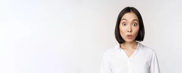 Close up retrato de jovem asiático modelo feminino olhando espantado para a câmera, sorrindo dentes brancos, de pé contra fundo branco — Fotografia de Stock