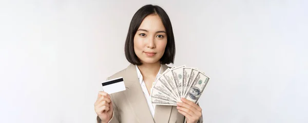 Närbild av asiatisk affärskvinna, kontor dam visar kreditkort och pengar dollar, stående i kostym över vit bakgrund — Stockfoto