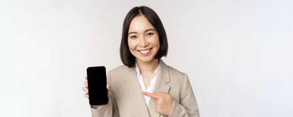 Retrato de mulher asiática corporativa mostrando interface de aplicativo de smartphone, tela do telefone móvel, de pé sobre fundo branco — Fotografia de Stock