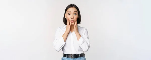 Imagen de modelo femenina asiática mirando sorprendida, mirando asombrada, reaccionando a las grandes noticias sorpresa, de pie sobre fondo blanco — Foto de Stock
