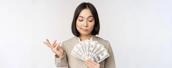 Citra wanita perusahaan Asia, pengusaha bahagia yang menunjukkan uang, dolar tunai dan berpikir, berdiri di atas latar belakang putih — Stok Foto