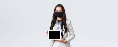 İş, finans ve istihdam, virüsü önleyen covid-19 ve sosyal uzaklık kavramı. Asyalı bayan ofis çalışanı dijital tablet görüntüleme ile toplantıda sunum yapıyor, yüz maskesi takıyor
