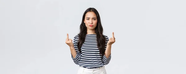 Estilo de vida, belleza y moda, concepto de emociones de la gente. Pouting molestado joven enojado-off asiático hembra mirada molesto y mostrando los dedos medios gesto grosero, fondo blanco — Foto de Stock