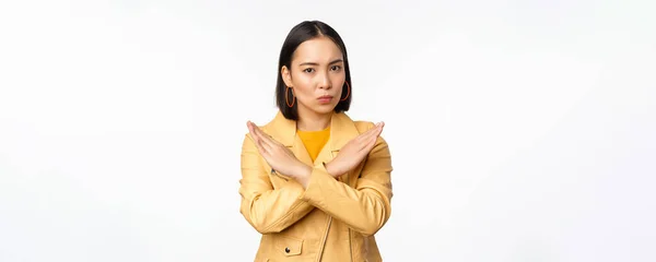 Stop gesture. Serious asian woman making arm cross, prohibit smth, rejecting, dislike and disapprove action, standing over white background — Stock Photo, Image