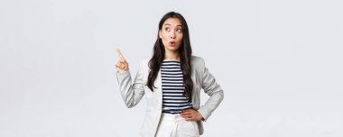 İş, finans ve istihdam, başarılı kadın girişimciler konsepti. Beyaz takım elbiseli neşeli başarılı iş kadını sol üst köşeyi işaret ediyor.