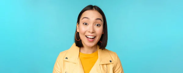 Close-up portret van natuurlijke aziatische meisje lachen, glimlachen en kijken gelukkig, staande over blauwe achtergrond — Stockfoto