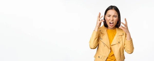 Asiático mulher zangada discutindo, apertando as mãos com raiva e gritando, gritando com rosto frustrado, de pé sobre fundo branco — Fotografia de Stock
