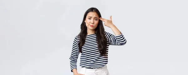 Lifestyle, people emotions and casual concept. Annoyed and pissed-off young woman cant stand this anymore, showing fake gun over head as if shooting herself from annoyance — Stok Foto