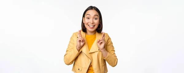 Portrait of excited asian woman looks hopeful, wishing, prayed or begging, waiting for news, standing over white background, smile antusias — Stok Foto